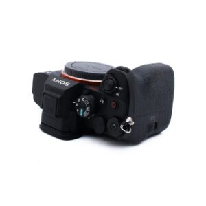 Sony A7 IV 3766-2 Musta Sony-digitaalikameran runko ylhäältä katsottuna, jossa näkyy erilaisia säätimiä, painikkeita ja kuvioitu kädensija ilman objektiivia.