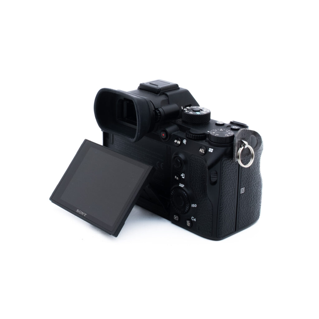 Sony A7R III 8638-3 Musta Sony-digitaalikamera näkyy takaa valkoisella taustalla, ja sen nestekidenäyttö on kallistettu vasemmalle. Erilaiset ohjauspainikkeet ja valitsimet ovat näkyvissä.