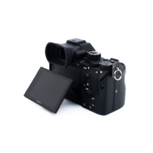 Sony A7R III 8638-3 Musta Sony-digitaalikamera näkyy takaa valkoisella taustalla, ja sen nestekidenäyttö on kallistettu vasemmalle. Erilaiset ohjauspainikkeet ja valitsimet ovat näkyvissä.