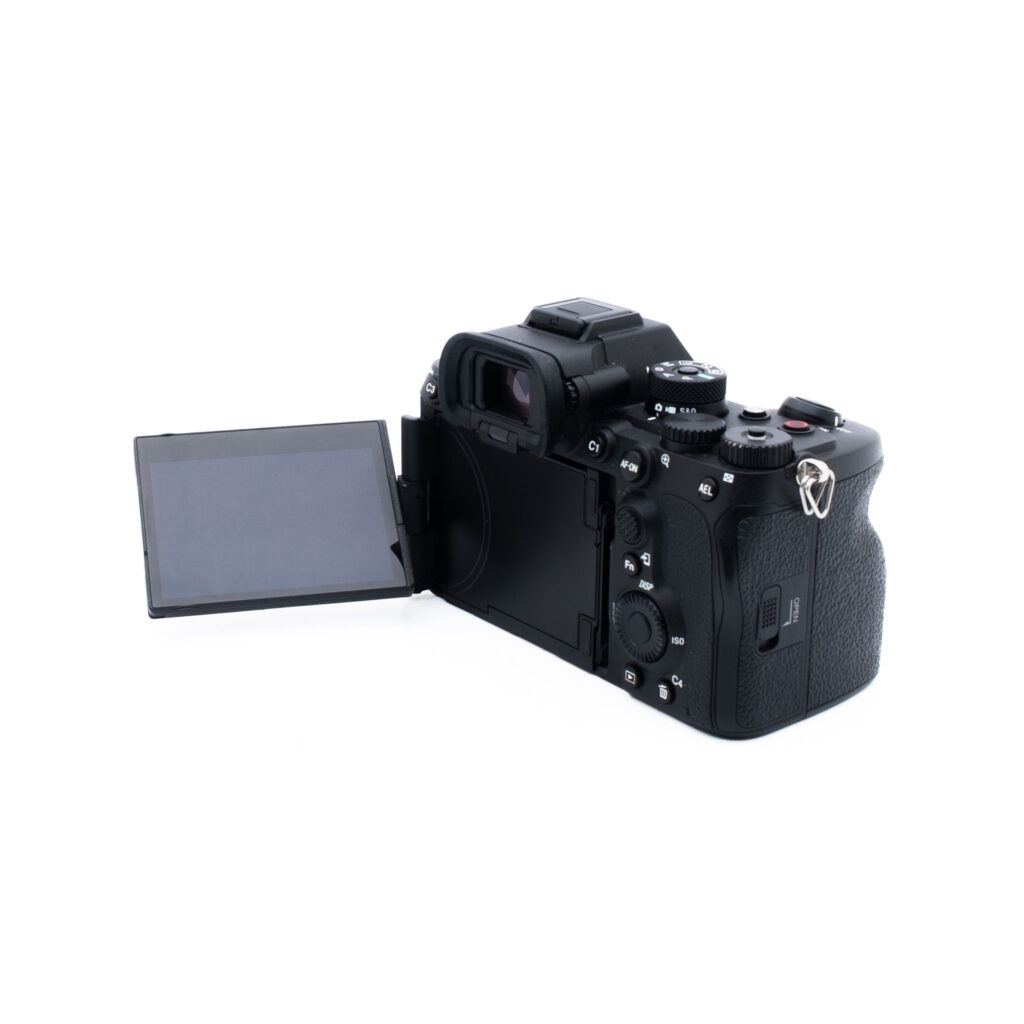 Sony A7R V 0622-3 Musta digitaalikamera, jonka nestekidenäyttö on käännetty sivulle, kuvattuna takaapäin valkoisella taustalla.