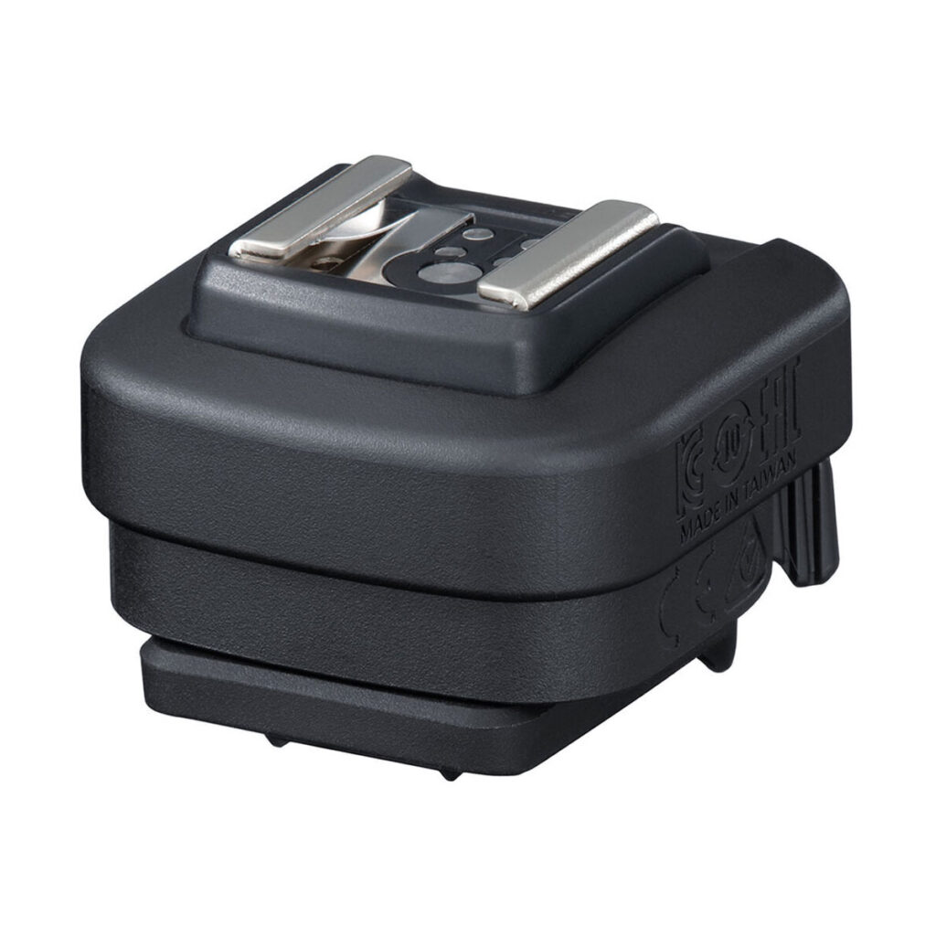 ad-e1 The Canon AD-E1 Multipurpose Flash Shoe Adapter is a black camera accessory with a metal hot shoe mount on top, designed to be attached to the camera for connecting external flashes or other devices.