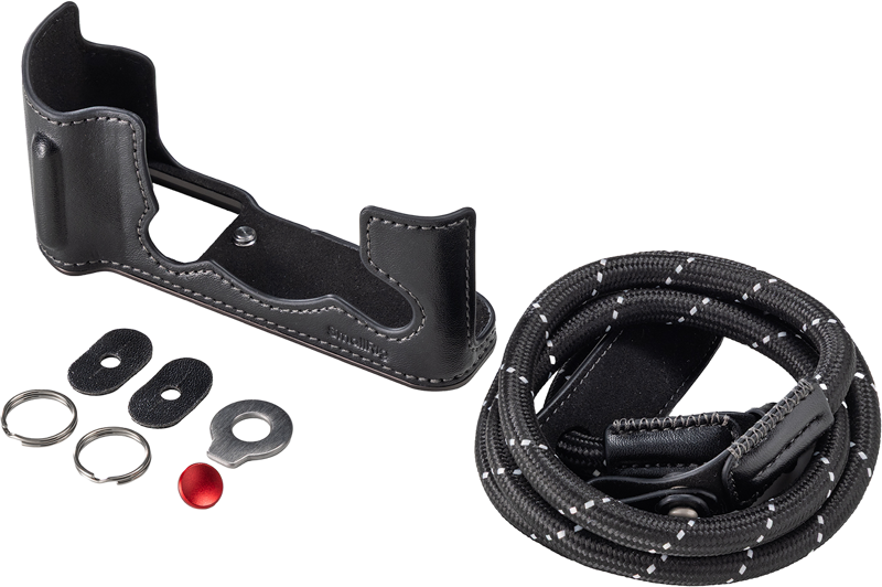 800q-01_135077 SmallRig 5669 Leather Half Case Kit for Fujifilm X-T30/II/III - nahkakotelo musta sisältää mustan nahkakotelon puolikotelon, mustavalkoisen kelaushihnan, kaksi metallirengasta, kaksi soikeaa liitintä, metallisen aluslevyn ja pienen punaisen napin, joka on sijoitettu valkoiselle pinnalle.