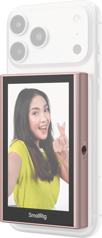 800q-01_135150 Keltaiseen paitaan pukeutunut nainen hymyilee ja tekee sormella sydäntä, kun hänen älypuhelimensa, joka on varustettu SmallRig 5746 Wireless Display Mirroring Adapter for Mobile Phone - Selfie Kit -laitteella, näkyy kameran linssit ylhäällä.