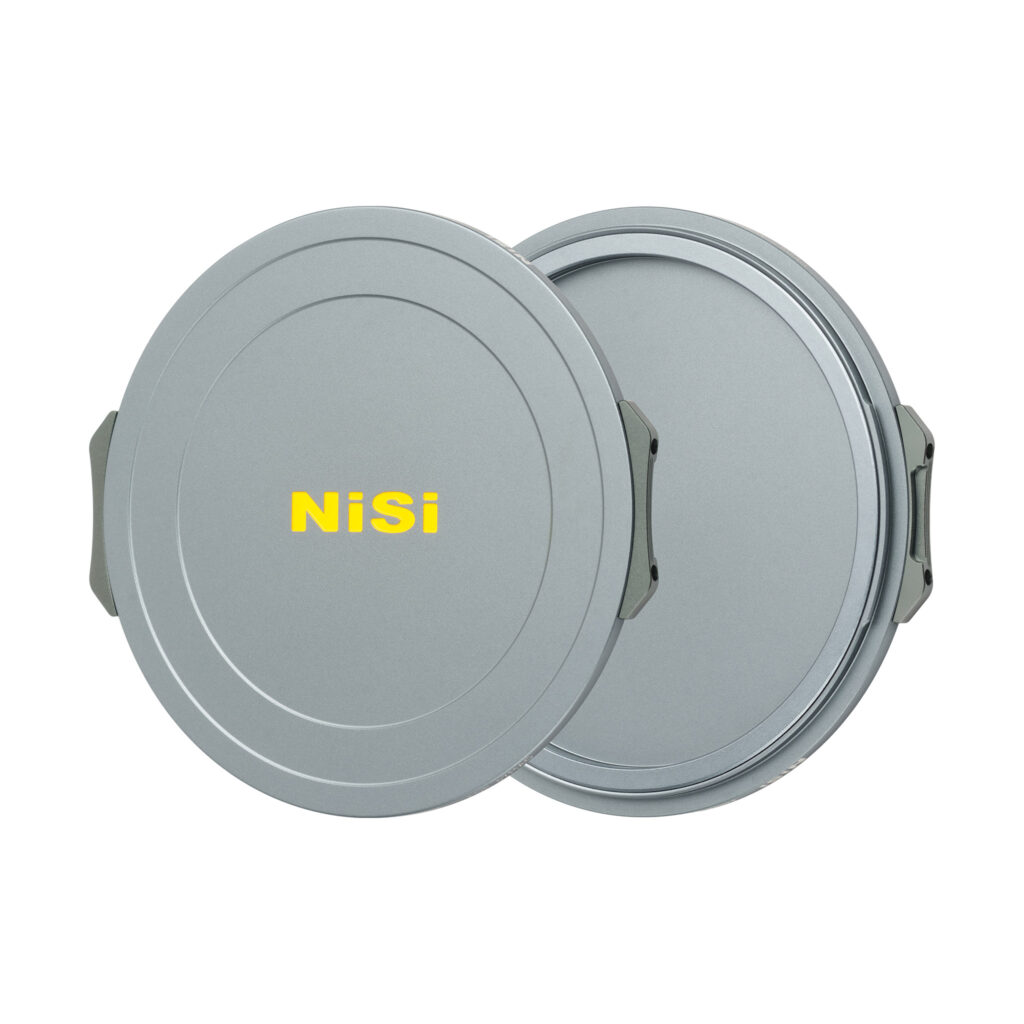 NisiMag67_15 Kaksi pyöreää, harmaata, metallista NiSi JetMag Pro Cap Kit -tulpat-suodatinkoteloa on esitetty päällekkäin, ja niiden etupuolella on keltainen "NiSi"-kirjain. Molemmissa koteloissa on sivuklipsit turvallista kiinnitystä varten.