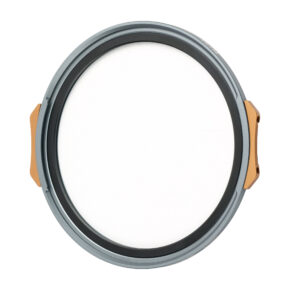 Pyöreä, litteä NiSi JetMag Pro 67mm Black Mist 1/4 -suodatin, jossa on harmaa ja kultainen reunus ja valkoinen keskus, joka muistuttaa kameran linssinsuojusta, näkyy valkoista taustaa vasten.