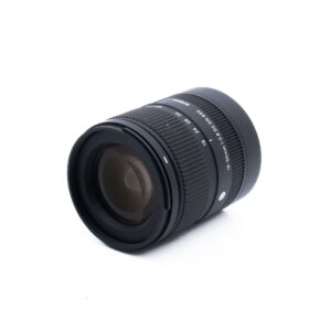 Sigma 18-50 dc dn-2 Sigma 18-50mm f/2.8 DC DN C Sony E (Kunto K5, Takuu 21kk) - Käytetty objektiivi, musta, jossa on näkyvät tarkennus- ja zoomausrenkaat sekä polttoväli- ja aukkomerkinnät, istuu vinossa valkoisella taustalla.