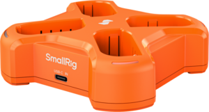 Vaalealla taustalla näkyy oranssi SmallRig 5748 nelikanavainen akkulaturi, jossa on neljä paikkaa ja sivussa USB-C IN -merkintä, joka on tarkoitettu akkujen lataamiseen.